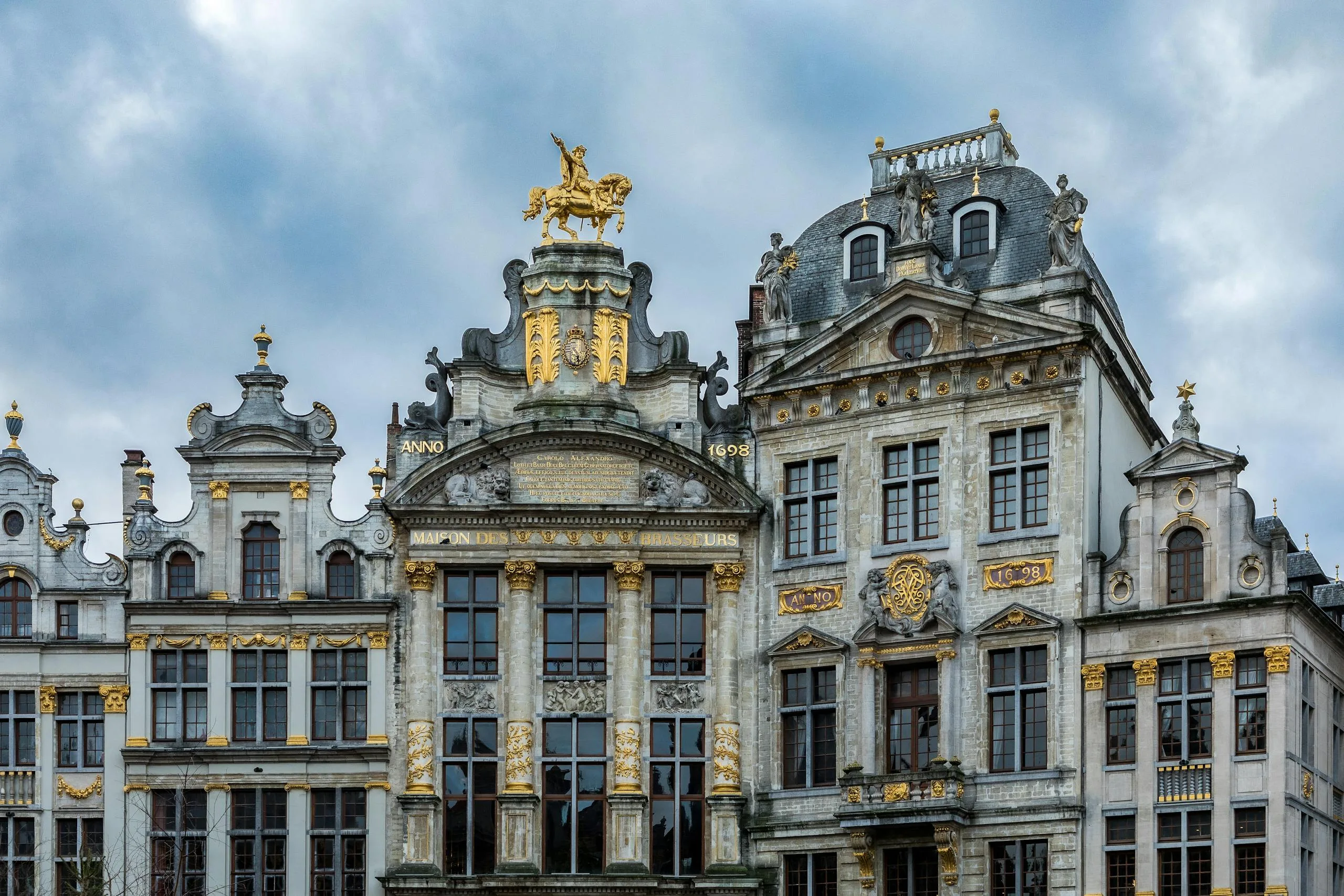 Stafford Affiliate Travel - Beautiful ornate buildings at the Grand Place in Brussels, showcasing Baroque style architecture under a cloudy sky.