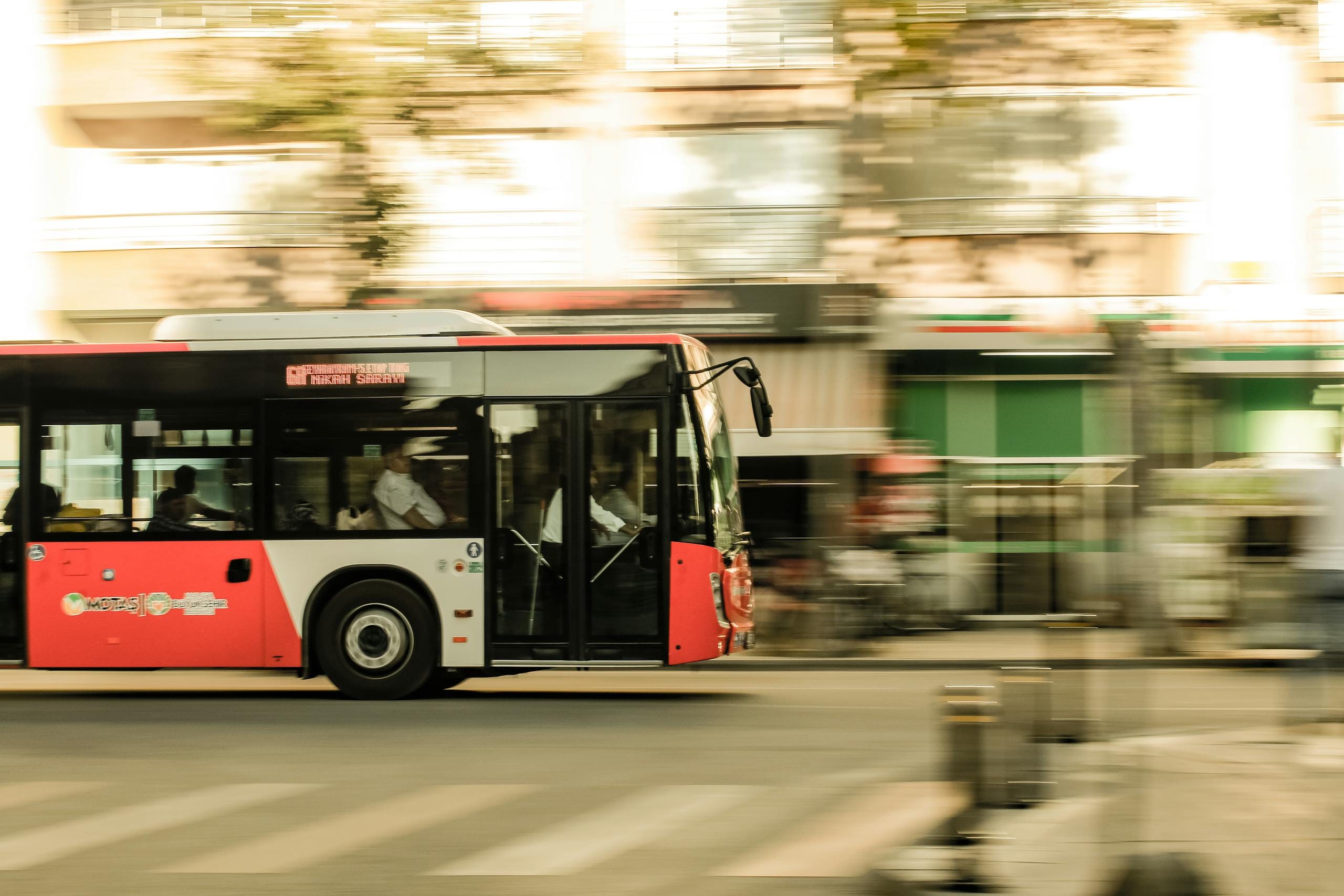 Stafford Affiliates Travel - A dynamic photo of a red bus speeding through an urban street, capturing city life.