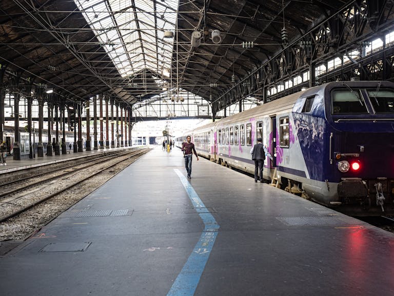 Stafford Affiliates Travel -v Interior view of a Paris train station showing a train and passengers on the platform.