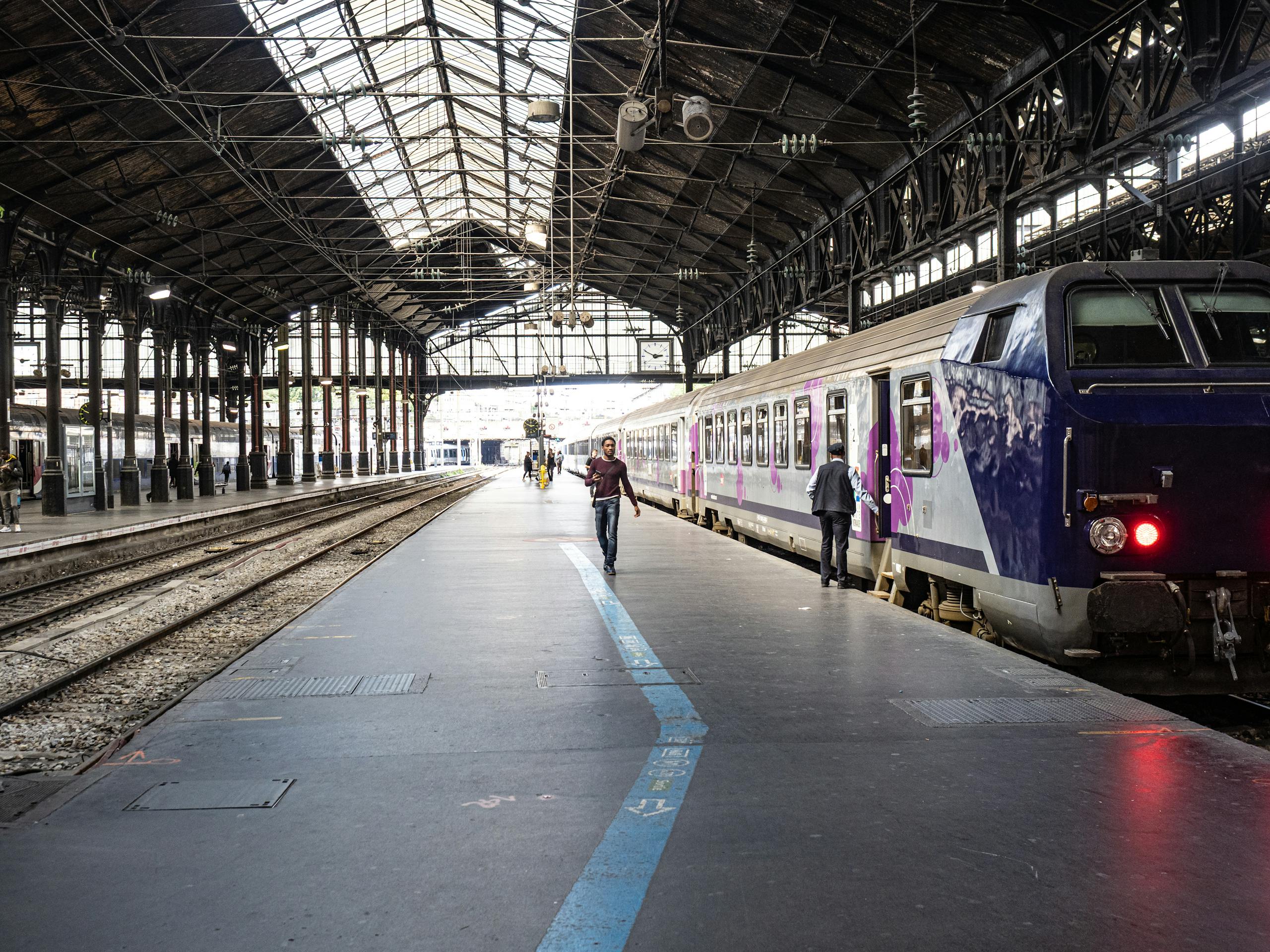 Stafford Affiliates Travel -v Interior view of a Paris train station showing a train and passengers on the platform.