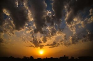 Stafford Affiliates Travel - Vibrant sunset with dramatic clouds casting shadows over a silhouetted cityscape.