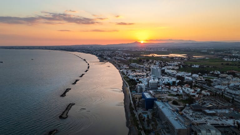 Aerial view of Limassol's coastline during sunset, showcasing the vibrant city and serene sea - Stafford Affiliates Travel