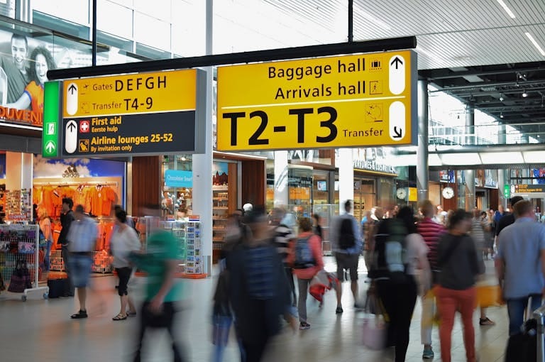 Crowded airport with motion blur and clear signage indicating baggage and arrival halls - Stafford Affiliate Travel