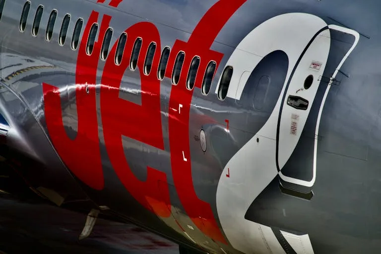 Detailed view of a commercial jet's exterior fuselage showing branding and windows - Stafford Affiliates Travel