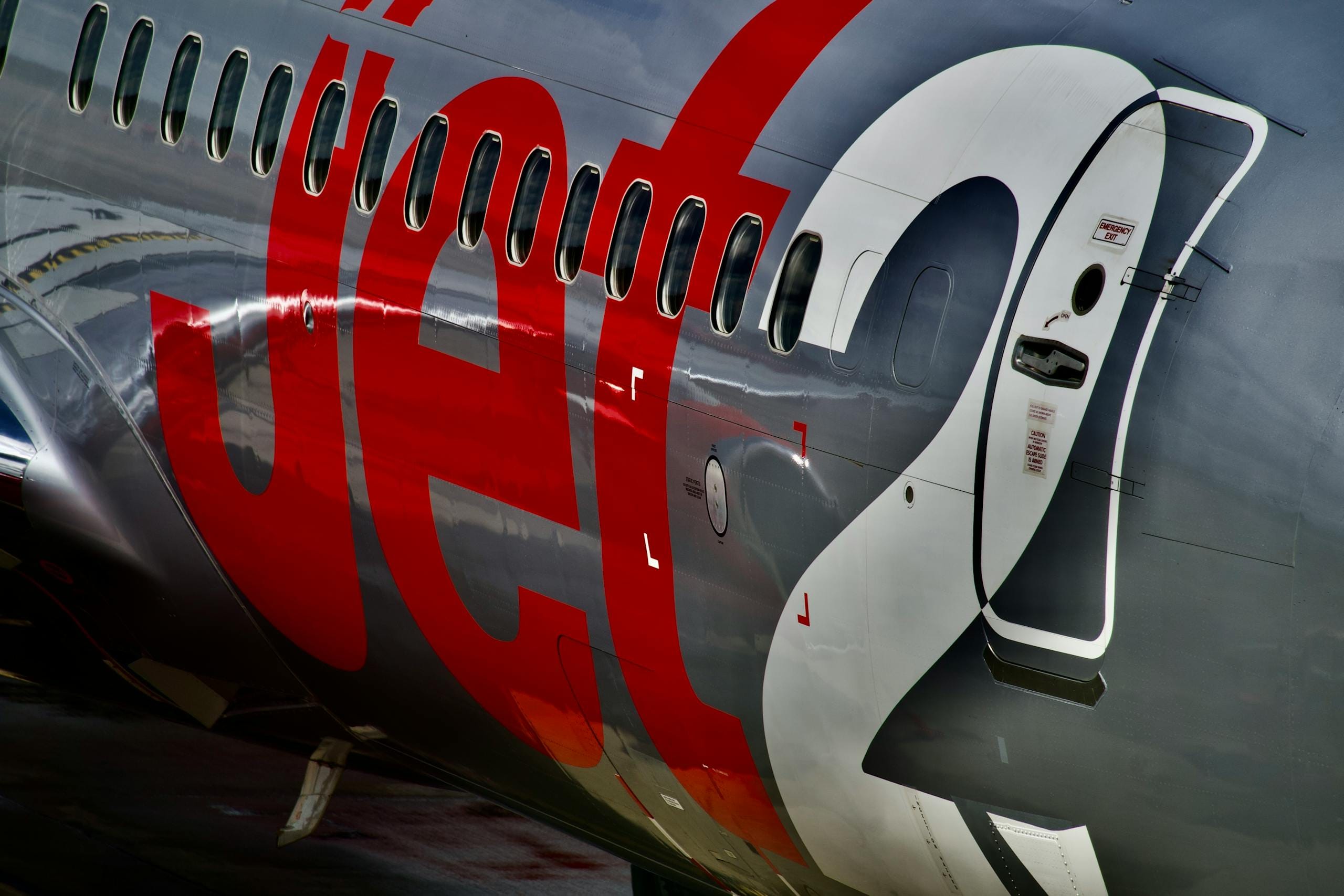 Detailed view of a commercial jet's exterior fuselage showing branding and windows - Stafford Affiliates Travel