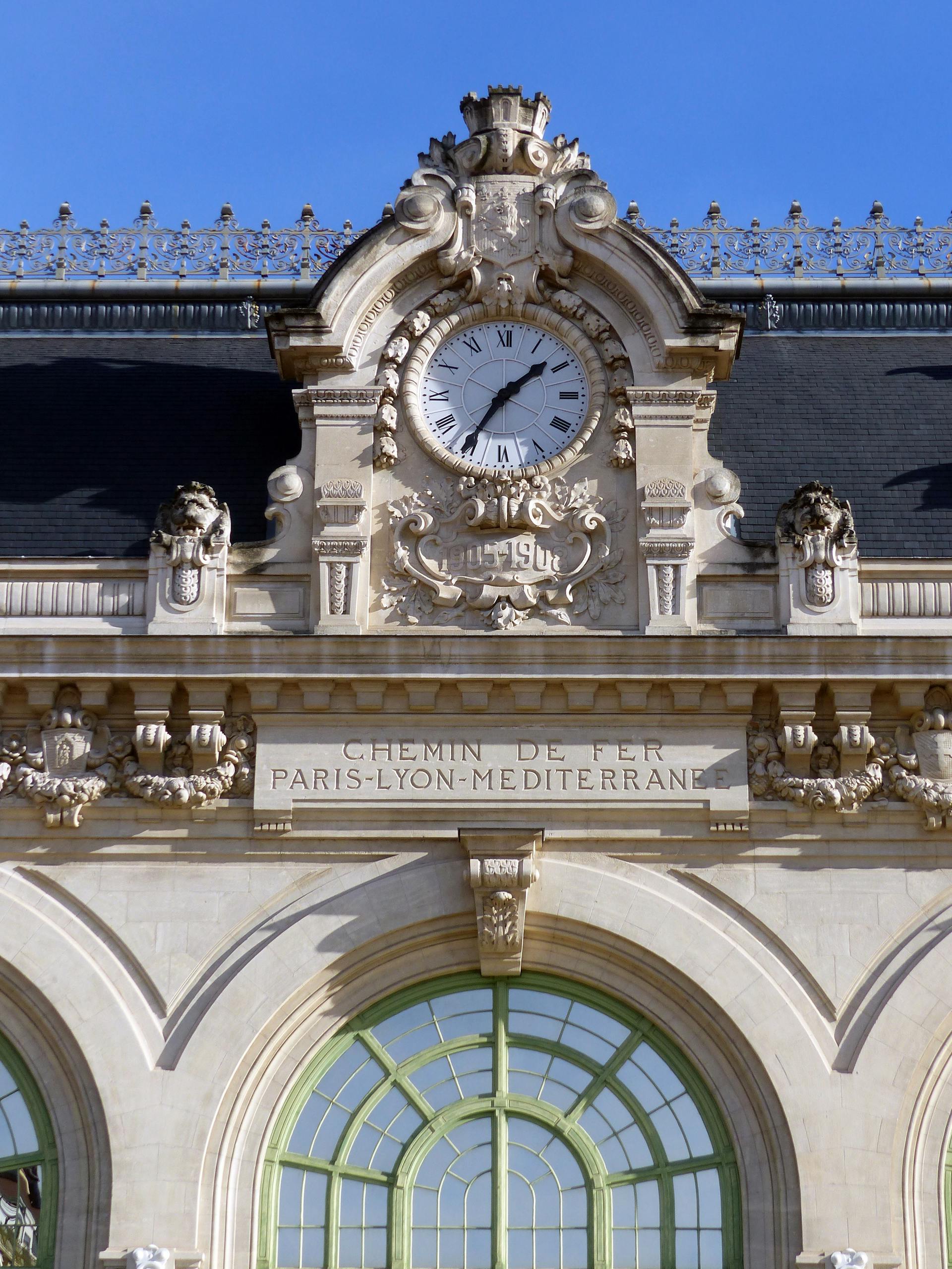 Detailed view of Gare de Lyon Railway Station facade with an ornate clock and Paris-Lyon-Mediterranean inscription. Stafford Affiliates Travel