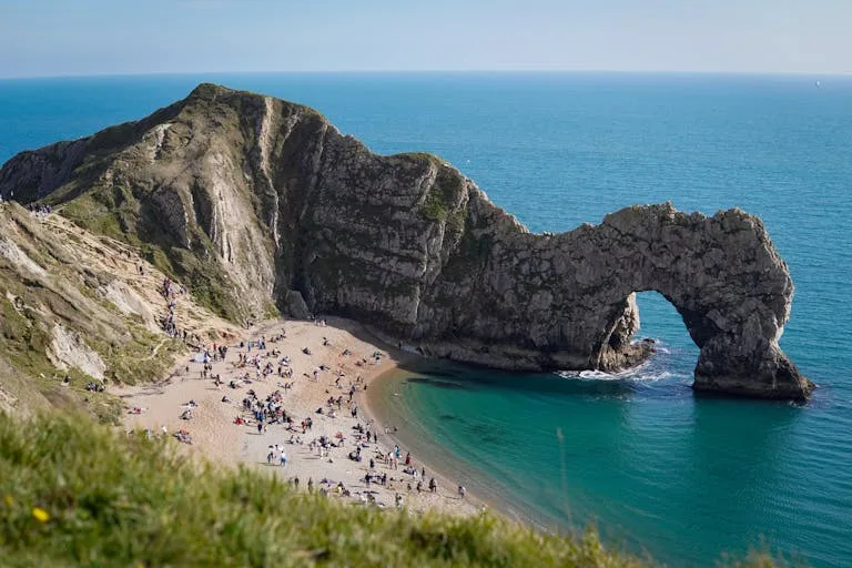 Lively scene at Durdle Door beach with iconic limestone arch and clear blue waters Stafford Affiliates Travel