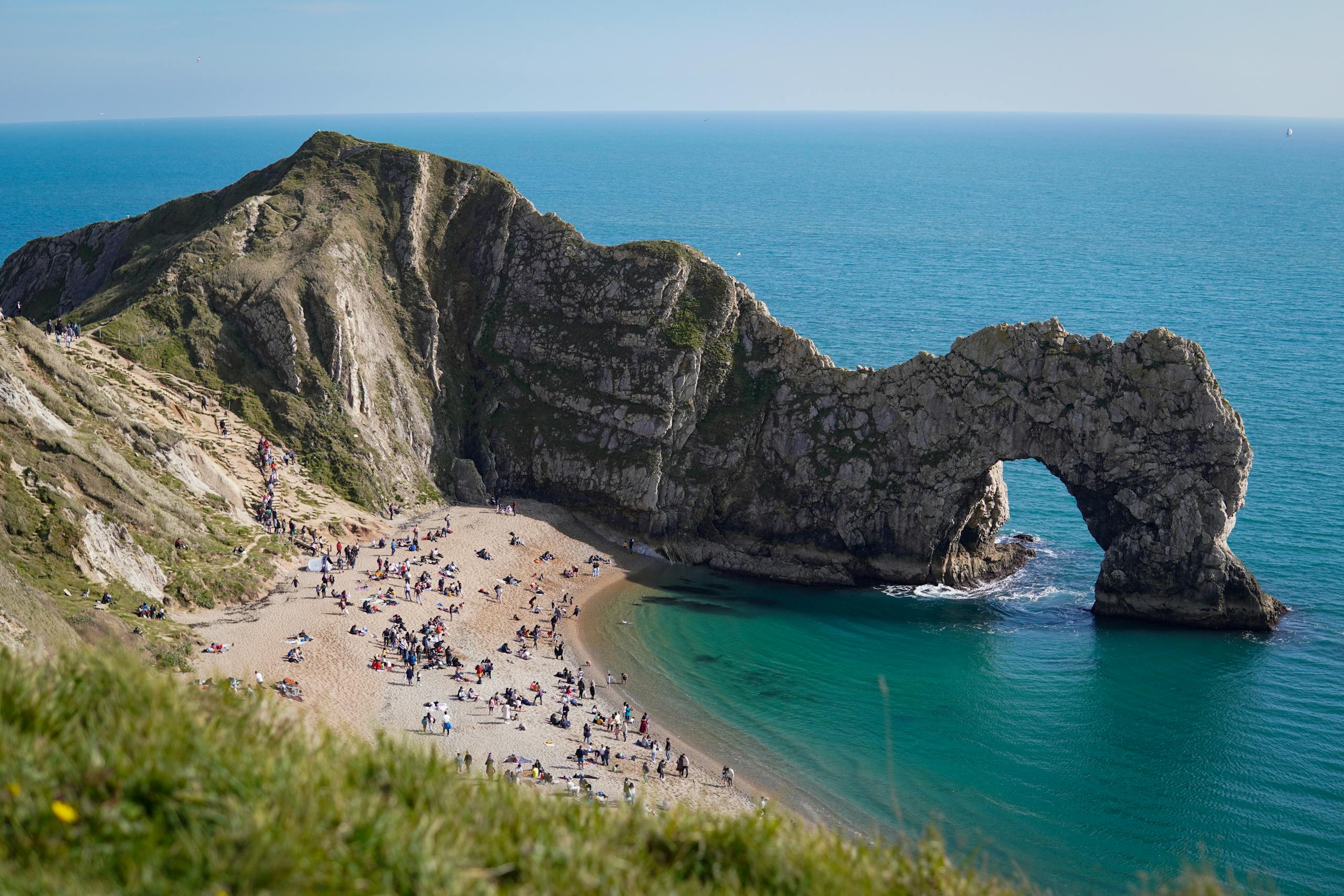 Lively scene at Durdle Door beach with iconic limestone arch and clear blue waters Stafford Affiliates Travel