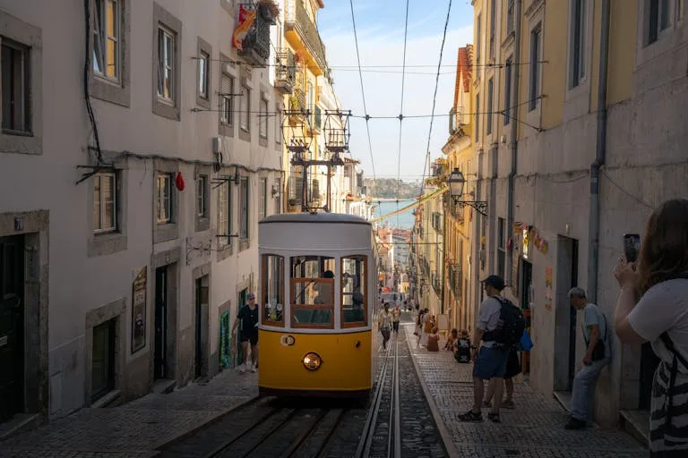 Stafford Affiliates Travel - A classic yellow tram navigates a steep street in Lisbon, Portugal, capturing the city's historic charm.
