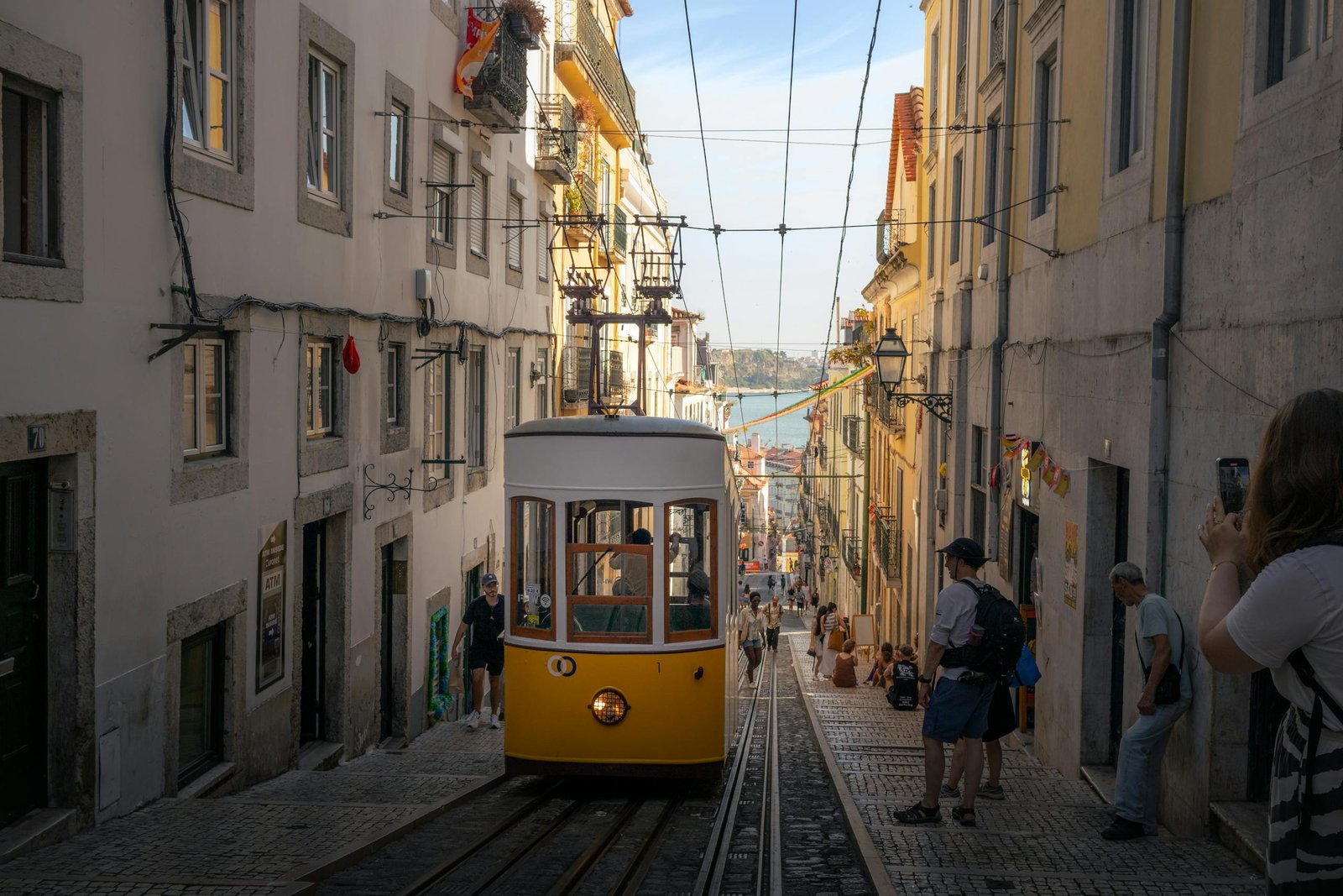 Stafford Affiliates Travel - A classic yellow tram navigates a steep street in Lisbon, Portugal, capturing the city's historic charm.