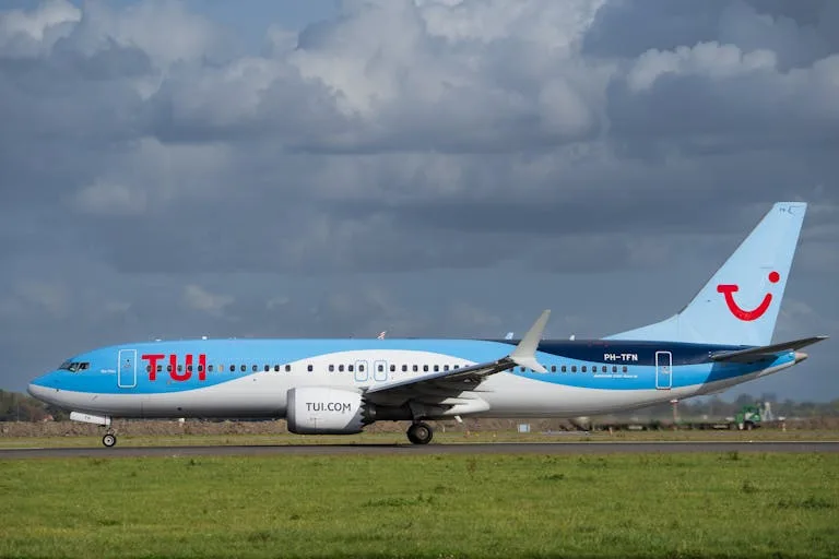 TUI Airlines jet taxiing on runway against cloudy sky, captured in daylight - Stafford Affiliates Travel