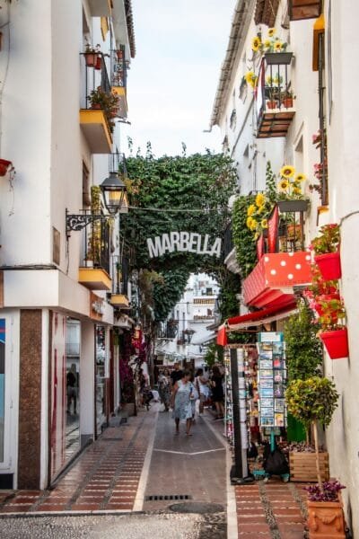 A picturesque alleyway in Marbella, Spain with vibrant flowers and quaint buildings, capturing urban charm - Stafford Affiliates Travel