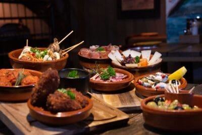 An inviting spread of various tapas dishes elegantly arranged in a cozy indoor restaurant ambiance - Stafford Affiliates travel