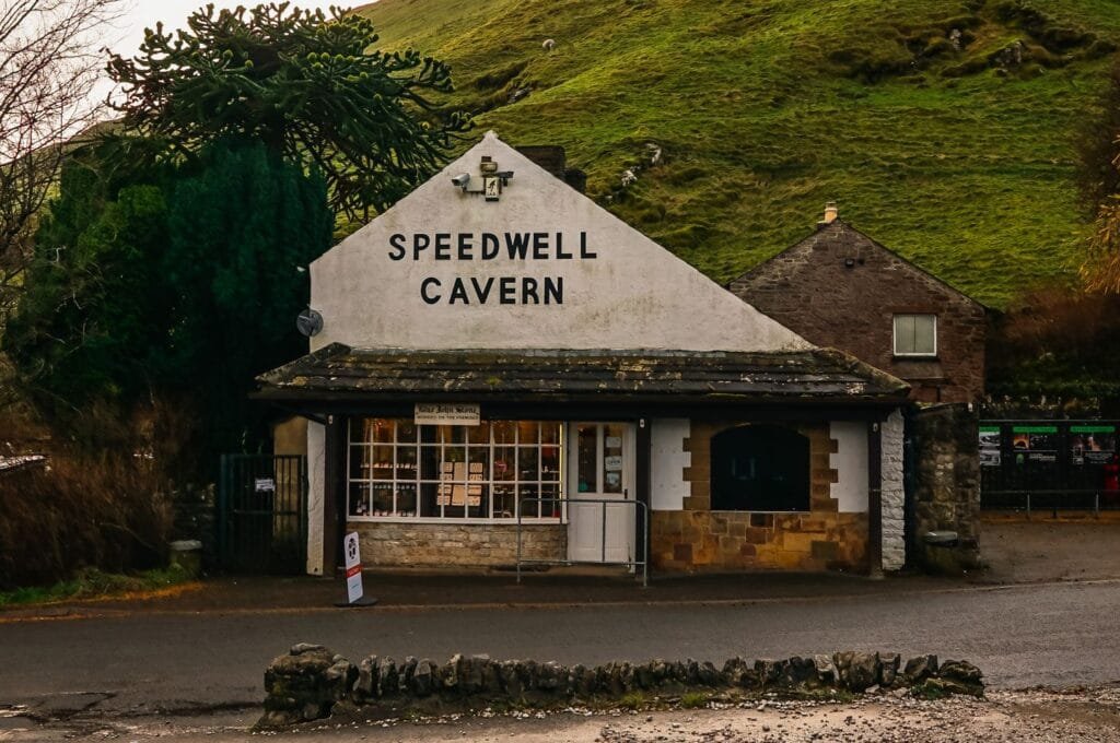 Picturesque Speedwell Cavern entrance with rolling green hills under a clear sky - Stafford Affiliates Travel