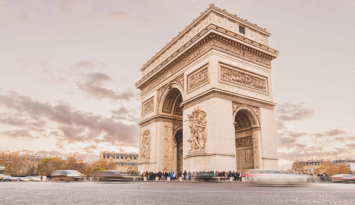 The majestic Arc de Triomphe in Paris captured with a vibrant sky at dusk, showcasing its grandeur - Stafford Affiliates Travel