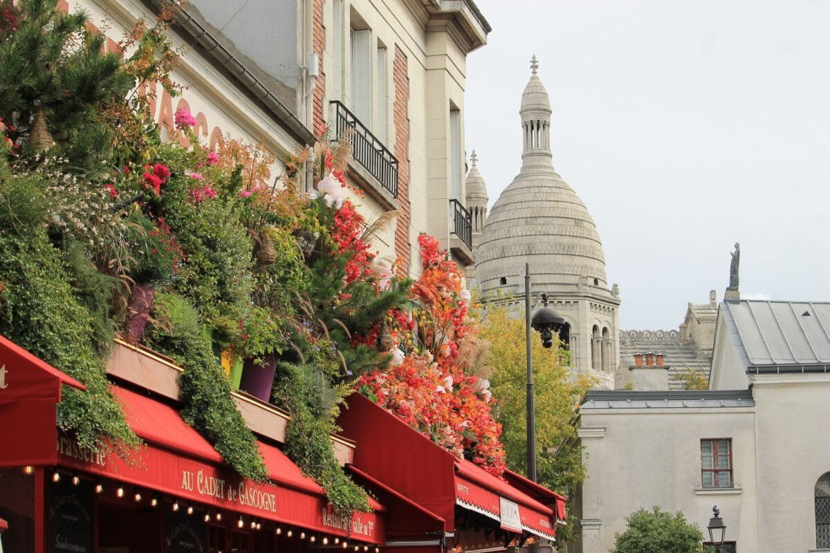 Vibrant floral display outside a cafe with Sacré-Cœur in the background, Paris - Stafford Affiliates Travel
