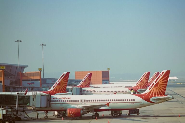 A fleet of Air India airplanes parked on the runway at an airport under clear blue skies - Stafford Affiliate Travel