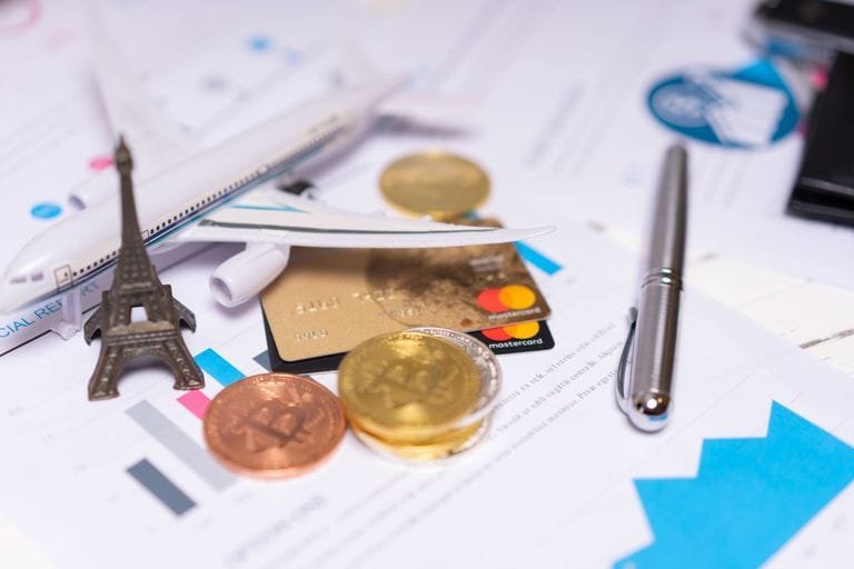 A travel finance concept featuring cryptocurrency, credit card, airplane model, and Eiffel Tower on financial documents Barrhead Travel - Stafford Affiliates Travel