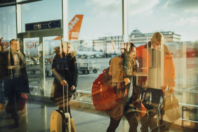 Passengers moving through an airport gate area with visible airplanes outside. easyJet Holidays Review: The Definitive UK Booking Guide / Stafford Affiliates Travel